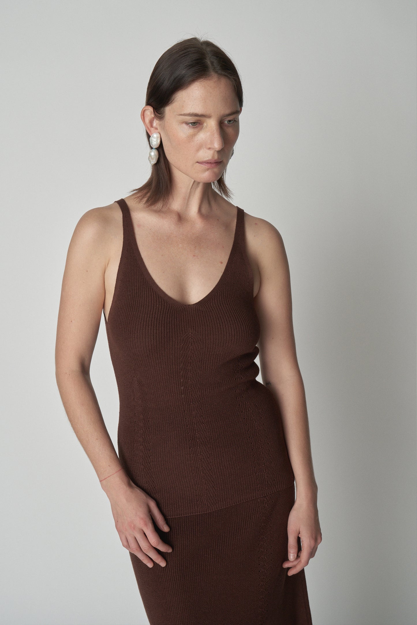 Torso shot of model wearing brown knit tank. 