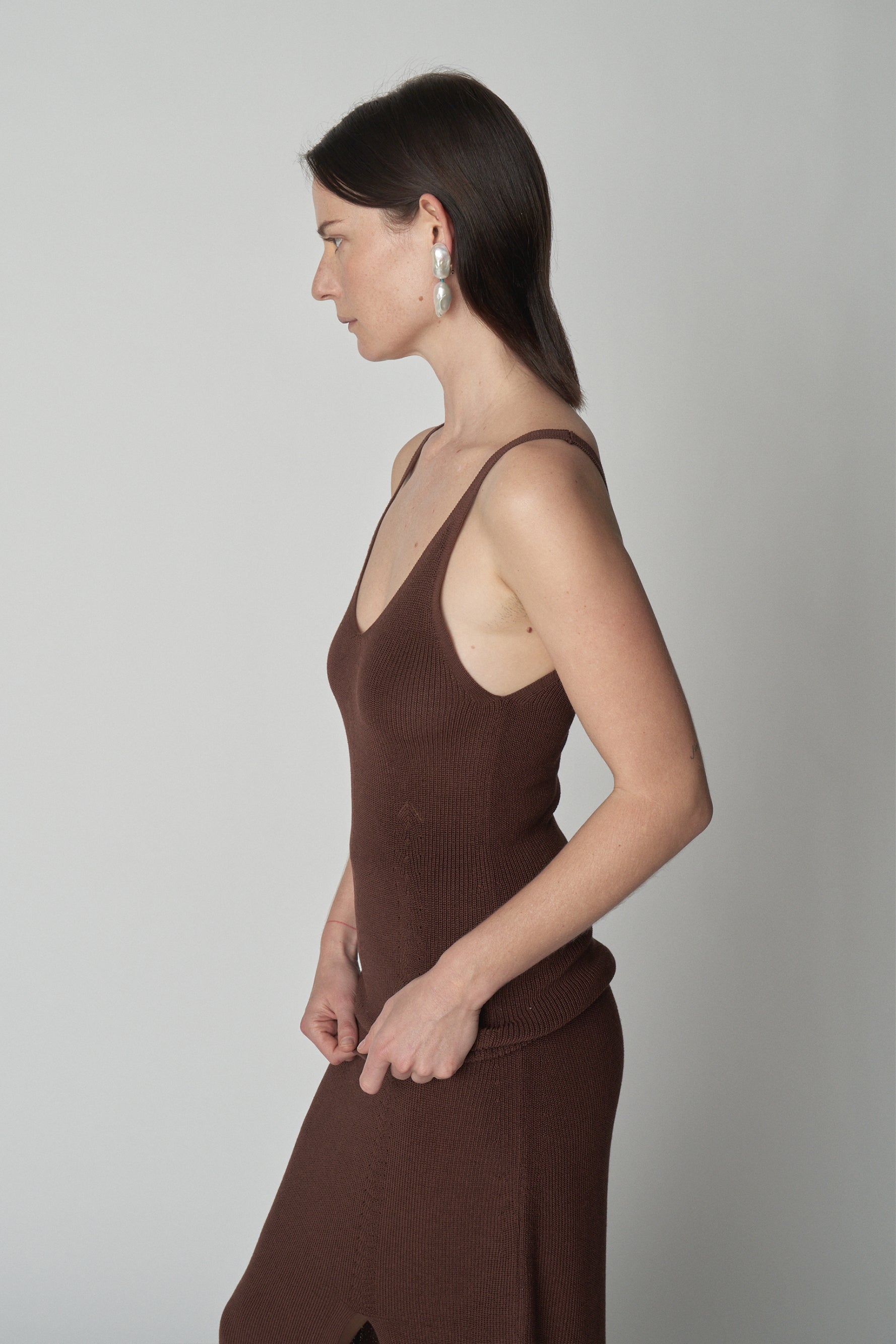 Side torso shot of model wearing brown knit tank. 