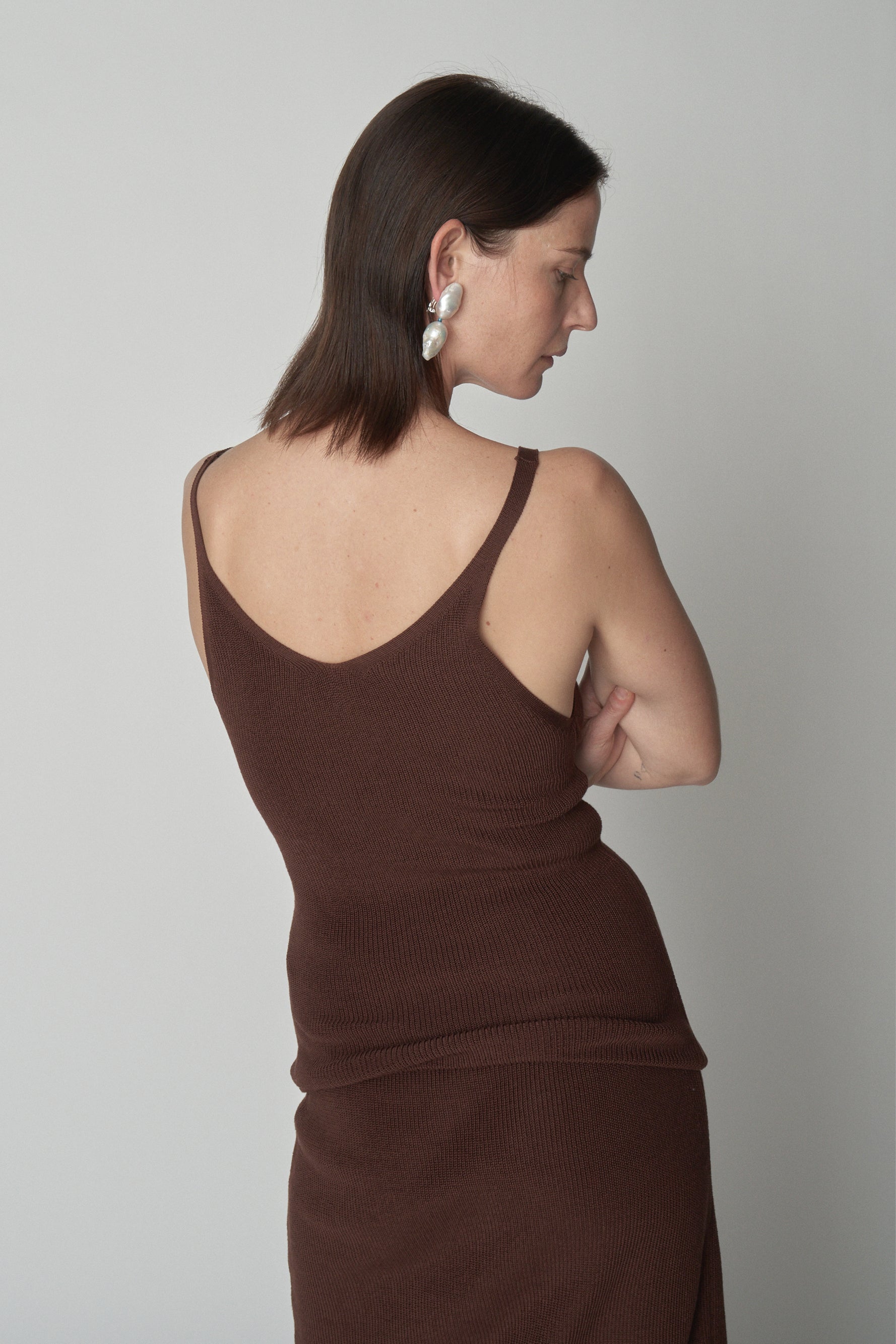 Back torso shot of model wearing brown knit tank. 