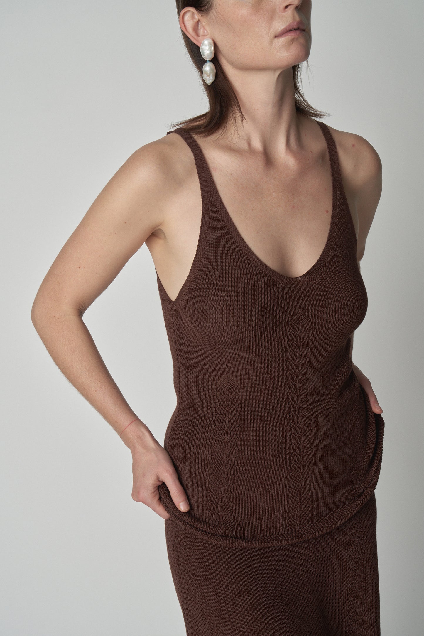 Torso shot of model wearing brown knit tank. 