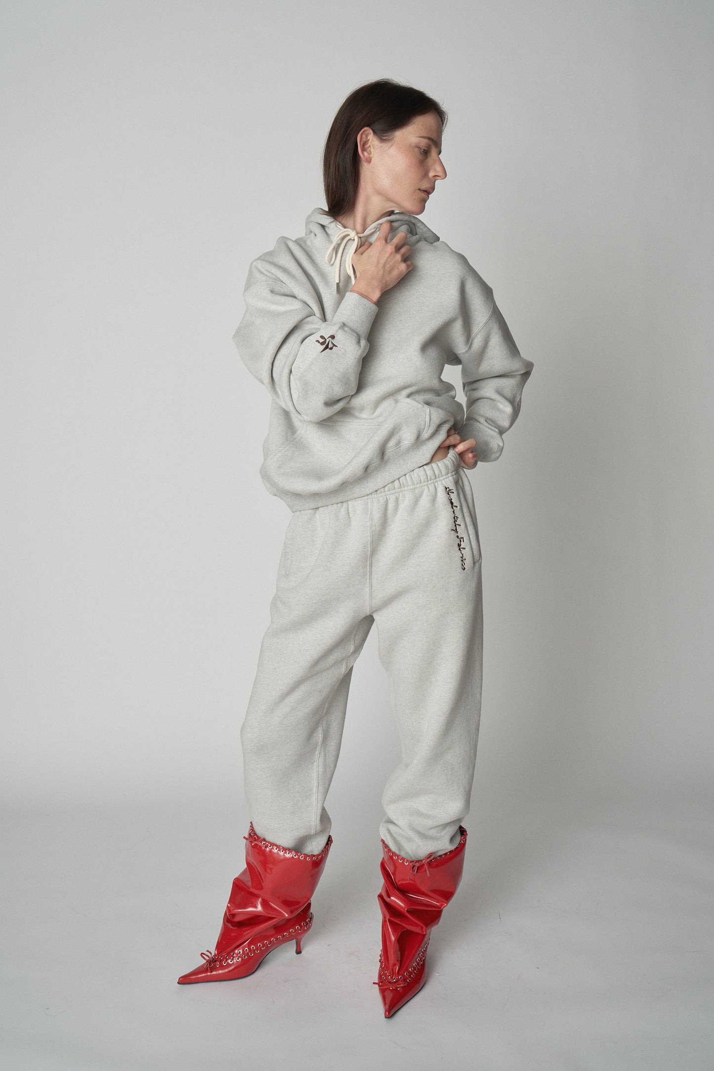 Full length front view of model wearing grey Absolutely Fabrics hoodie and sweatpants with red heeled boot.