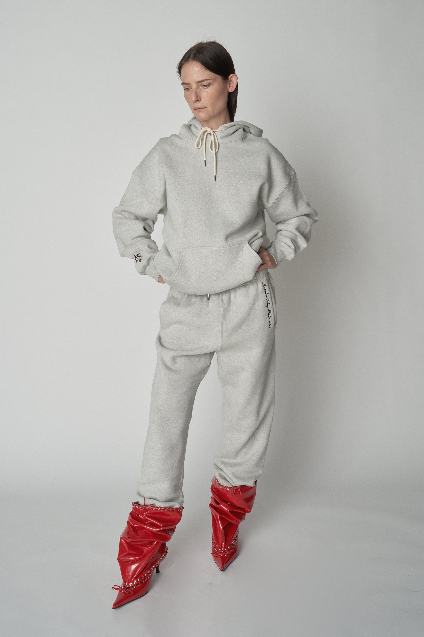 Full length front view of model wearing grey Absolutely Fabrics hoodie and sweatpants with red heeled boot.