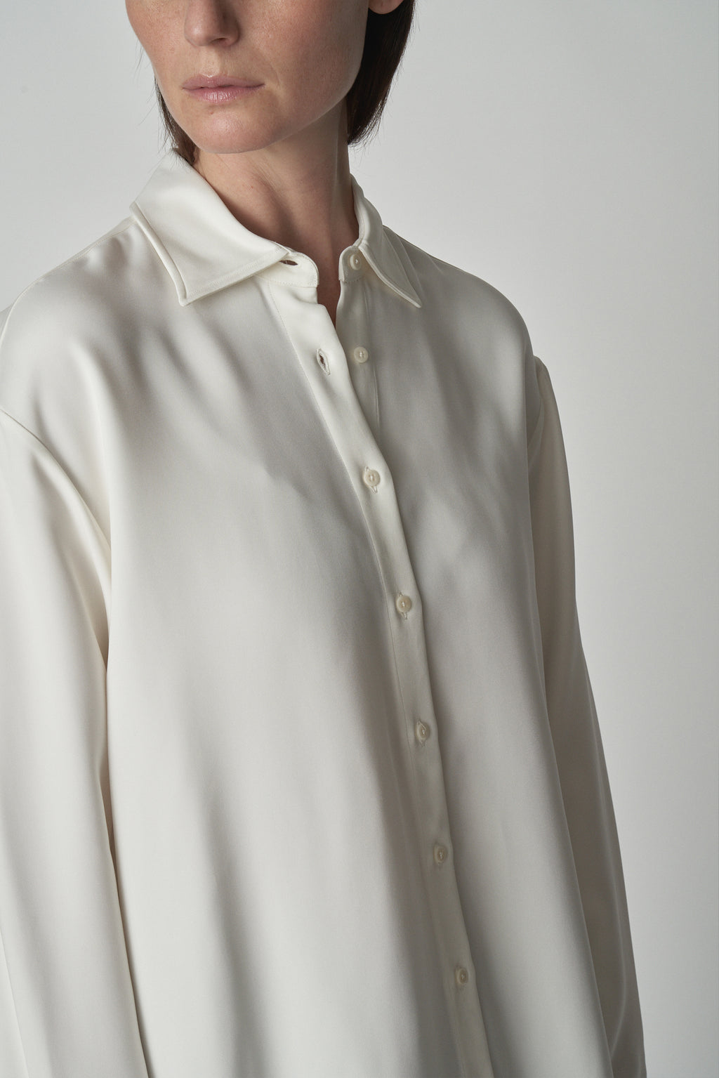 Detail shot of collar and button placket of white relaxed shirt. 