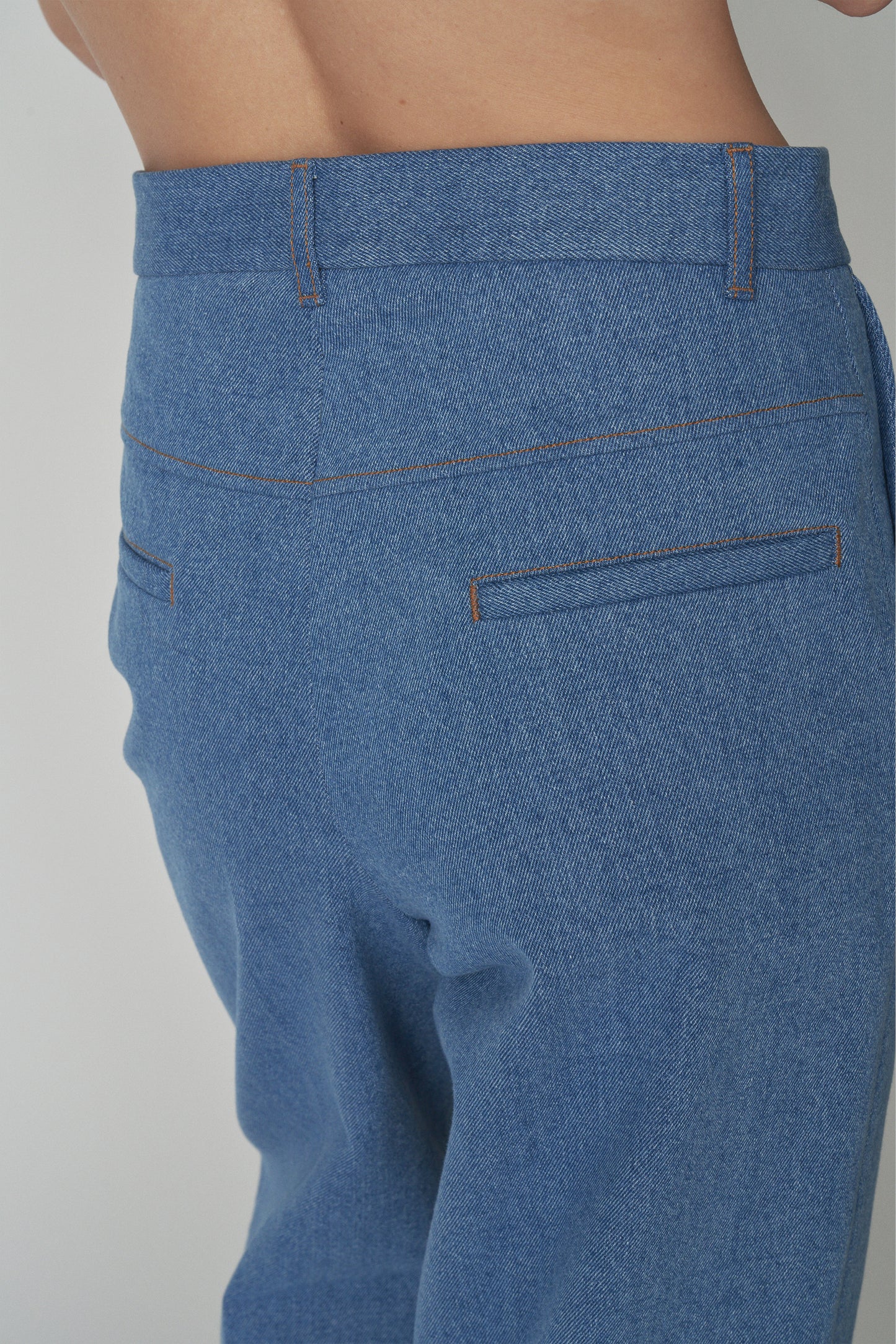 Detail shot of back pocket of denim trousers. 