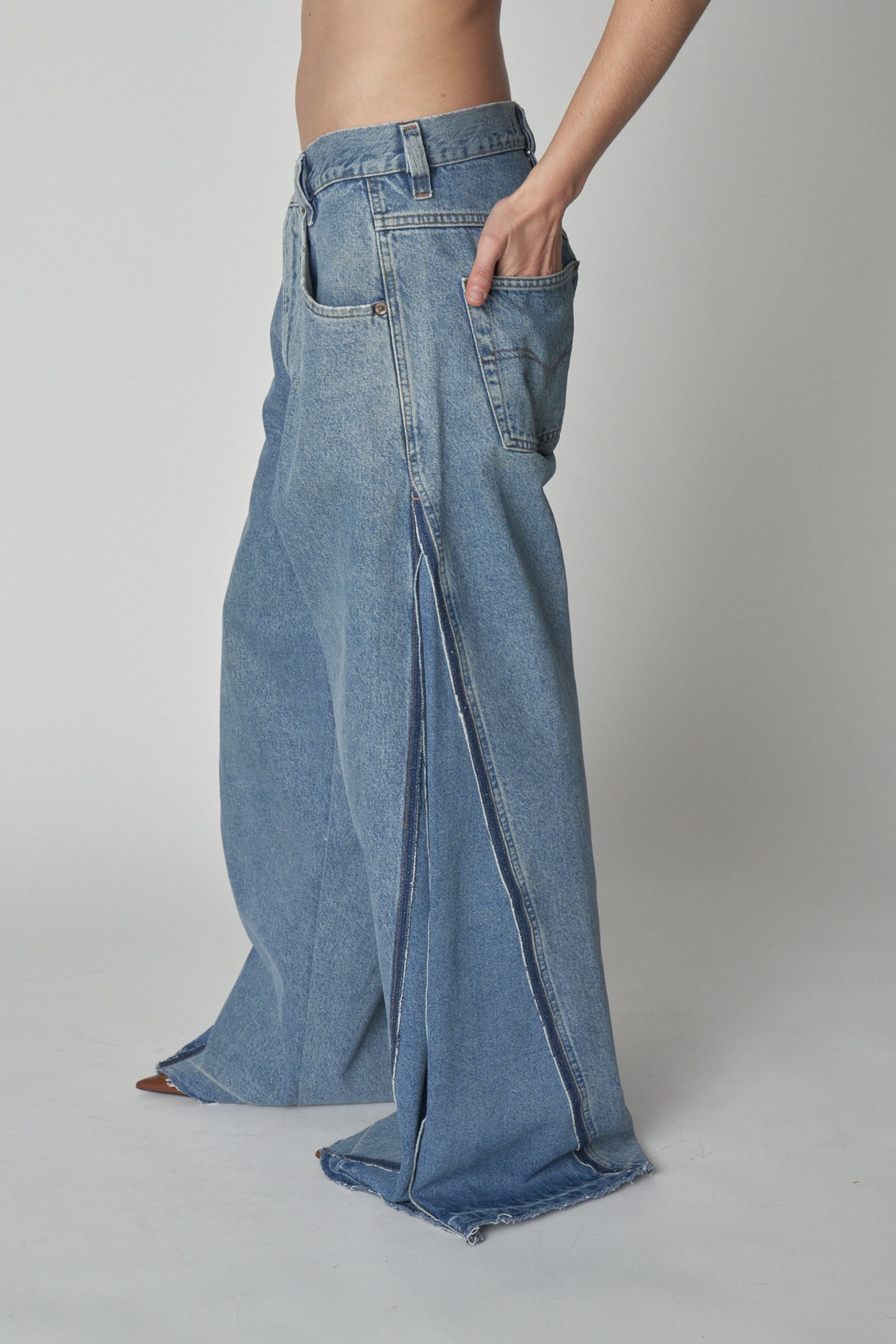 Side view of model wearing wide-leg jeans with additional denim panel.