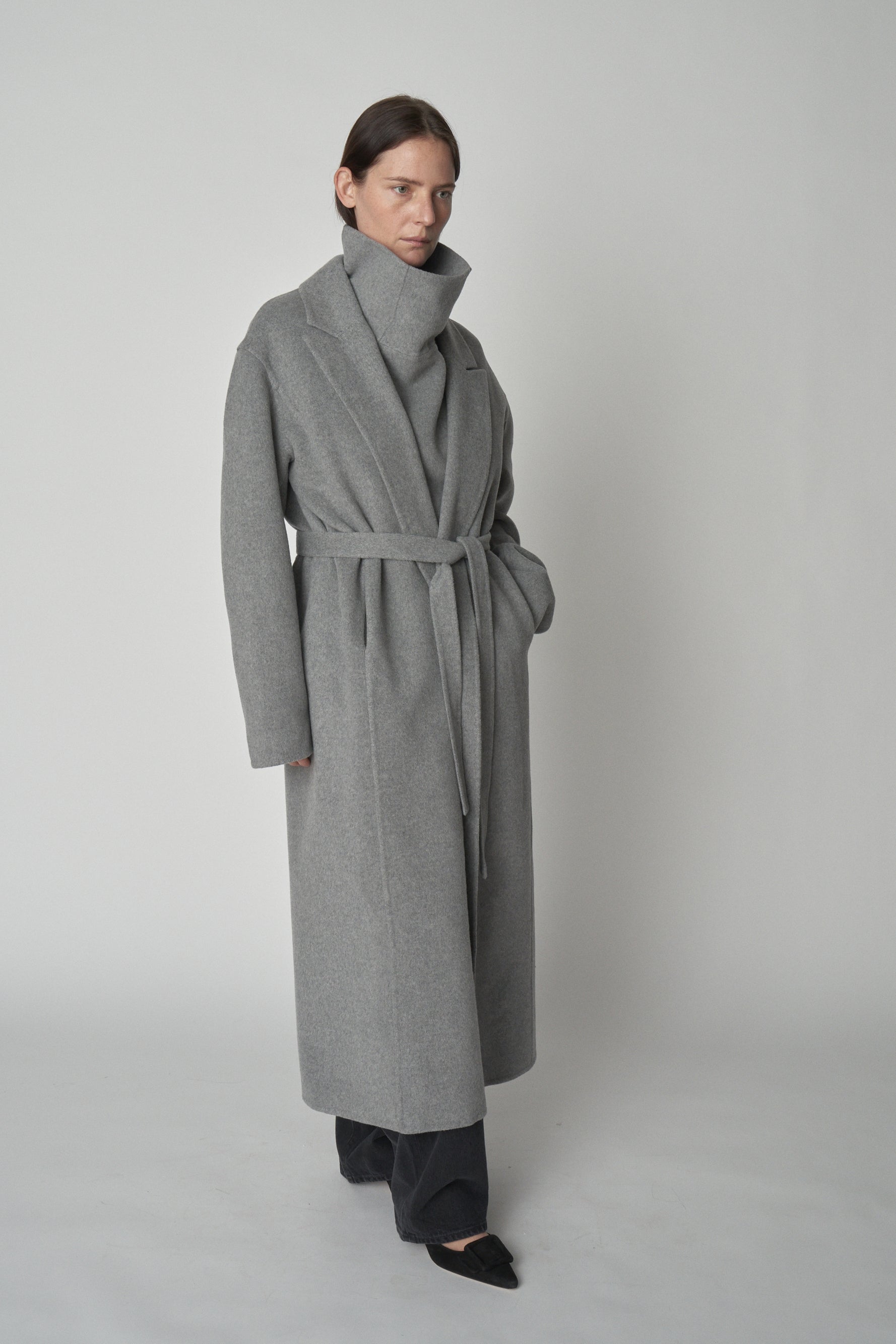 Model wearing grey trench-style wool coat. 