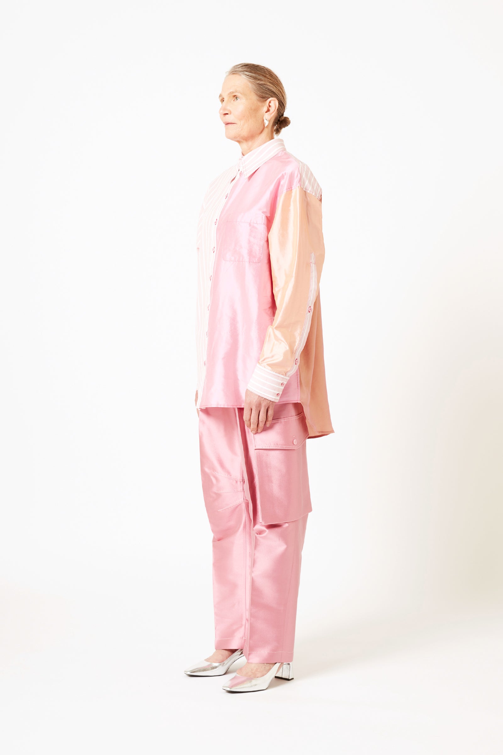 Side view of model wearing mauve silk cargo pants and pink striped cotton shirt.