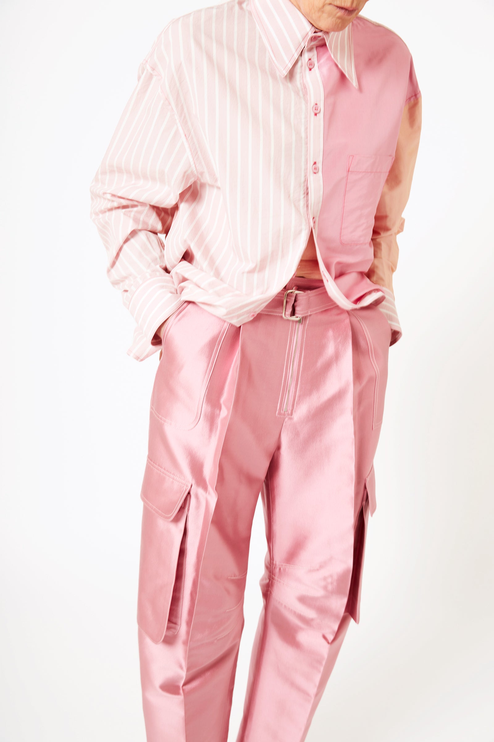 Detail shot of model wearing mauve silk cargo pants and pink striped cotton shirt.