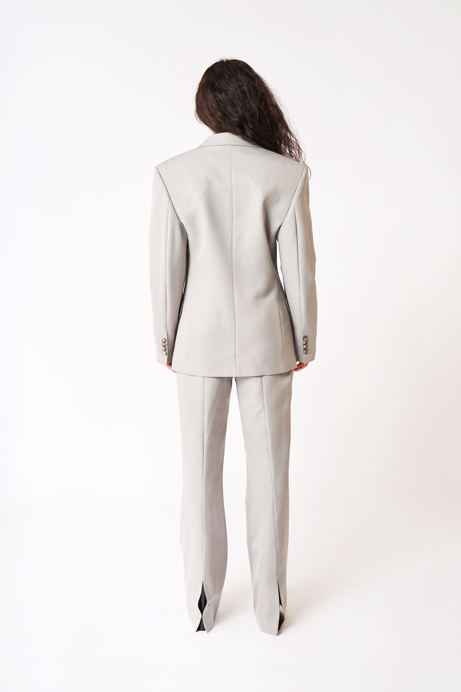 Model's back in Bettter grey suit with strong shoulder and lare trouser. 