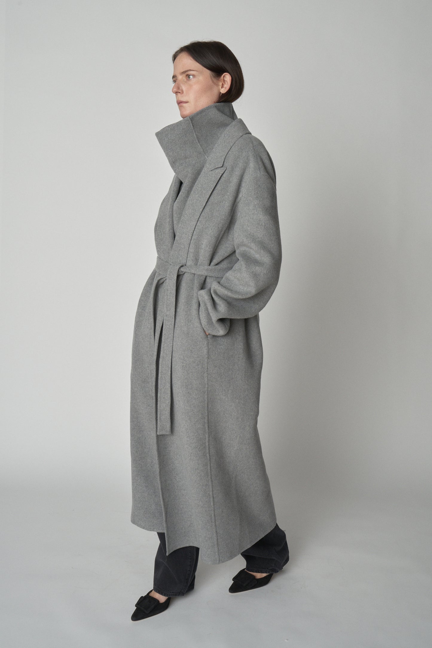 Model wearing grey trench-style wool coat. 